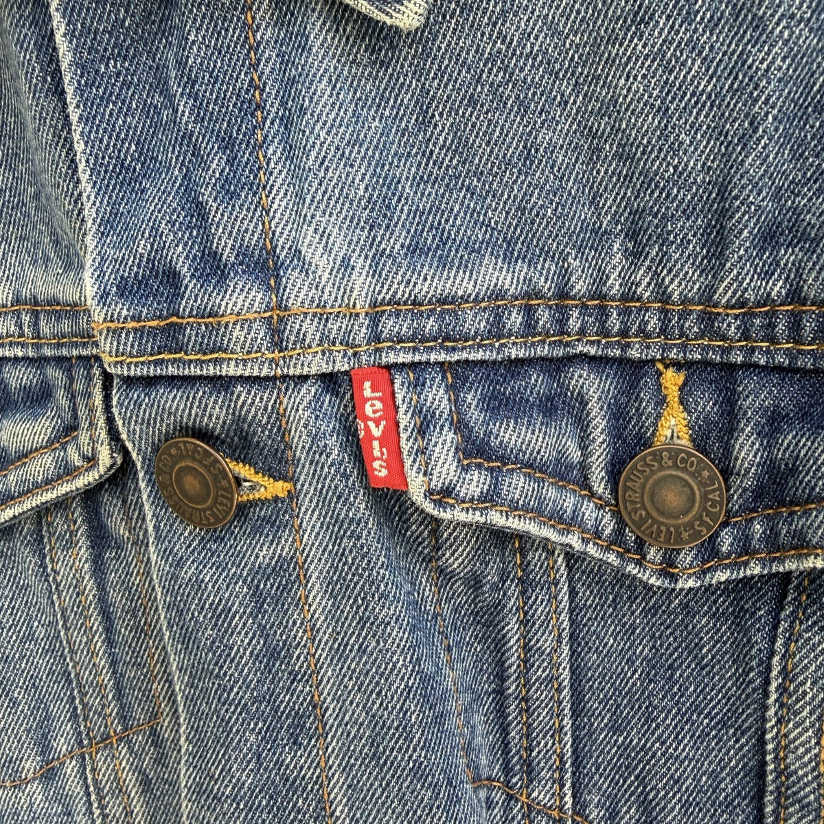 Détail de la patte de boutonnage et de l'étiquette rouge